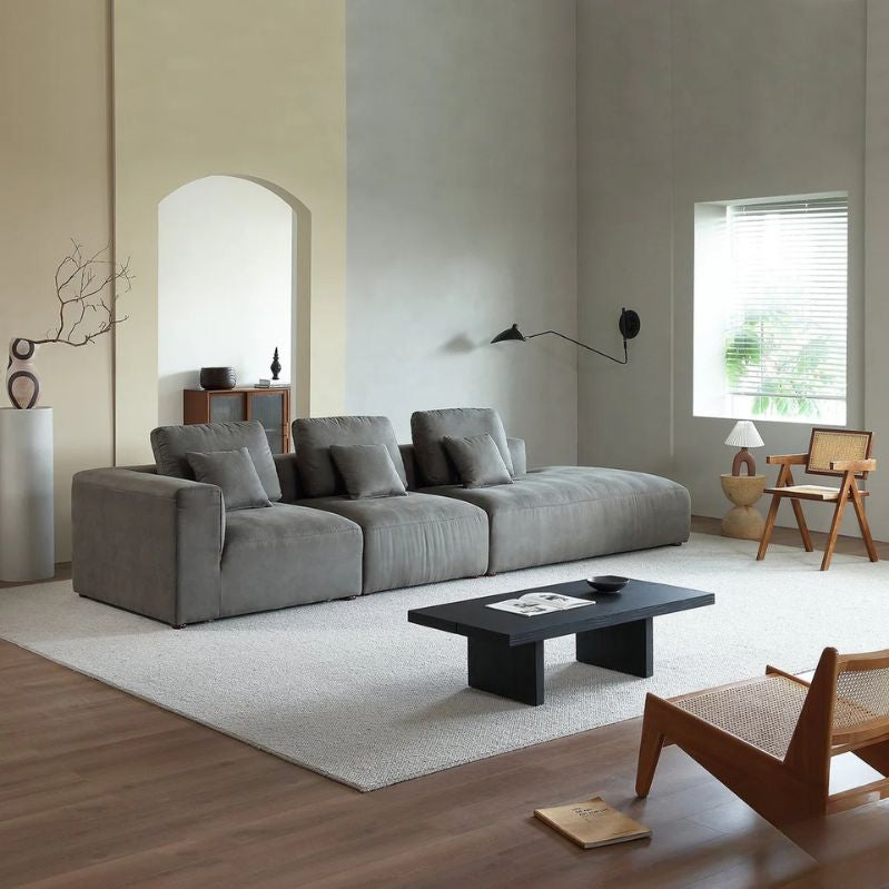 "Modern living room with a gray sofa, coffee table, and wooden chairs."