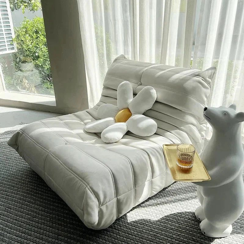 "White plush toy on a cushioned surface with a bear-shaped chair and a glass of water."