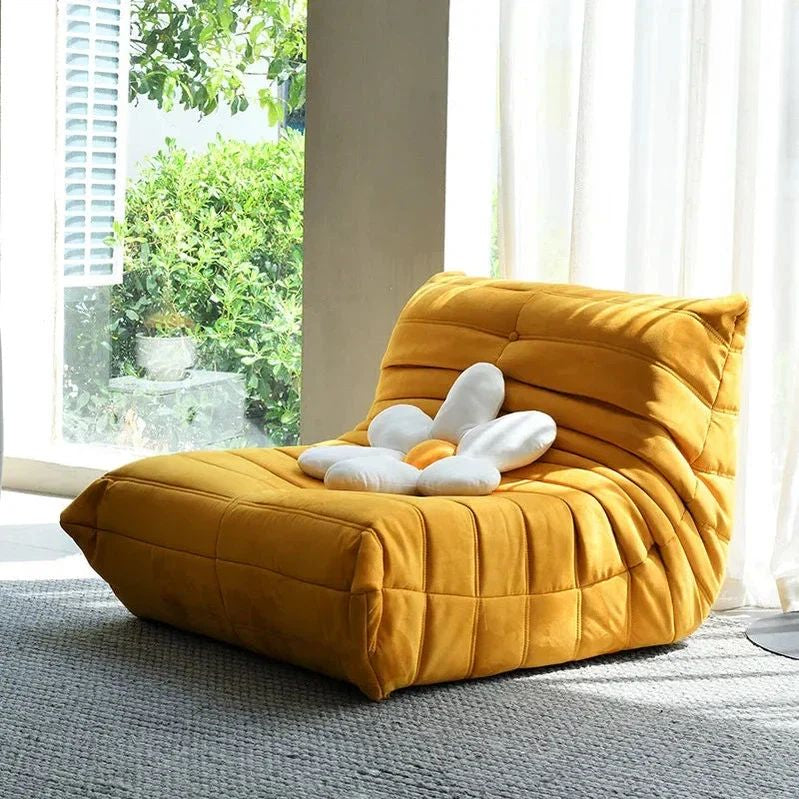 "Yellow bean bag chair with a white flower plush toy in a room with large windows."