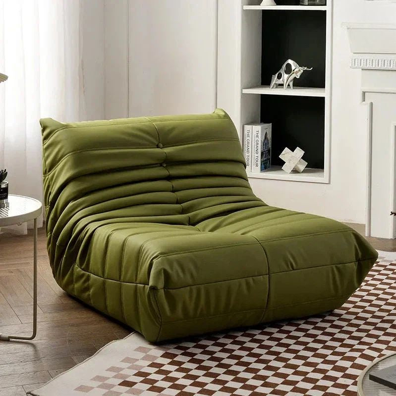 "Green bean bag chair in a room with a checkered rug and white walls."