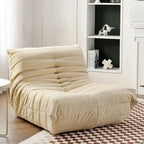 "Beige bean bag chair in a room with a bookshelf and checkered rug."
