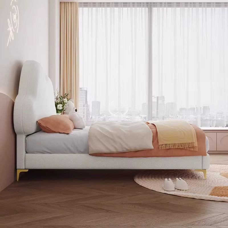 "Modern bedroom with a bed, pillows, and a window with sheer curtains."