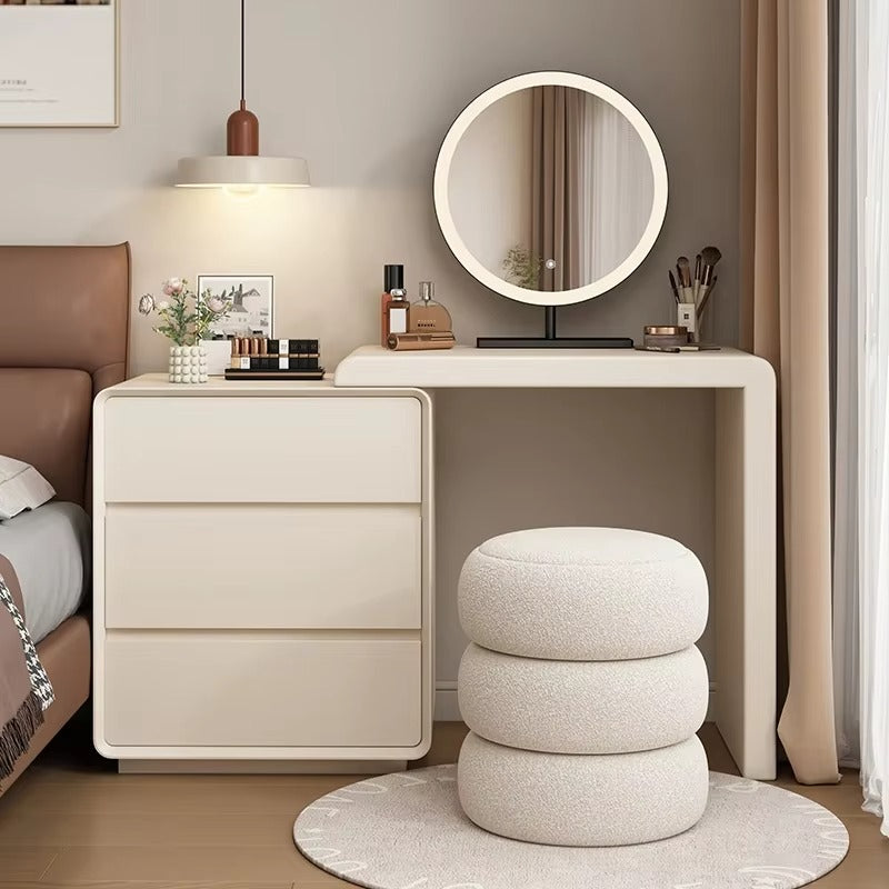 "A modern simple Nordic solid wood makeup dressing table with a round mirror and a padded stool. The table is beige, and the stool is white with a textured design."