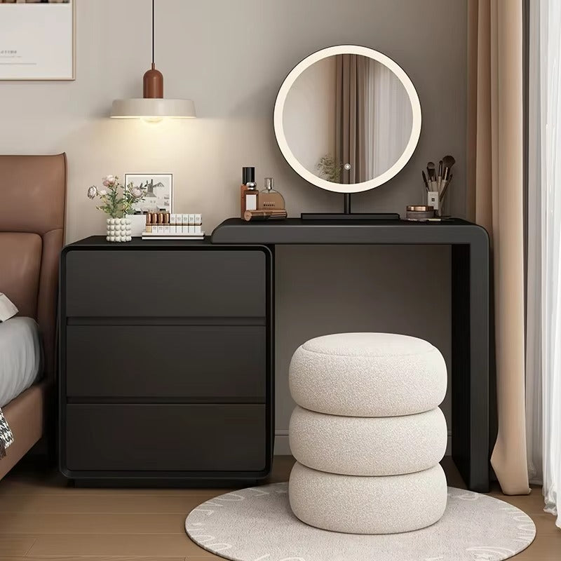 "Modern Simple Makeup Dressing Table \nModern bedroom setup with black dresser, round mirror, and white ottoman."