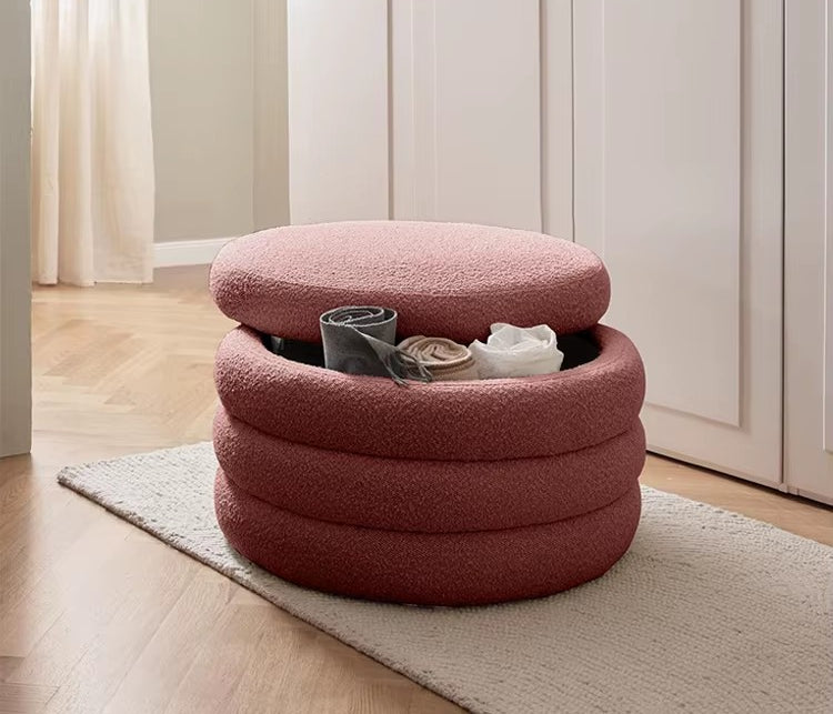 "Pink ottoman with storage compartments on a wooden floor."