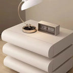 "Modern nightstand with a lamp and digital clock displaying the time."