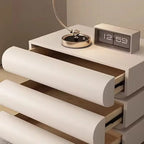 "Modern nightstand with clock, lamp, and rolled-up paper on a neutral background"