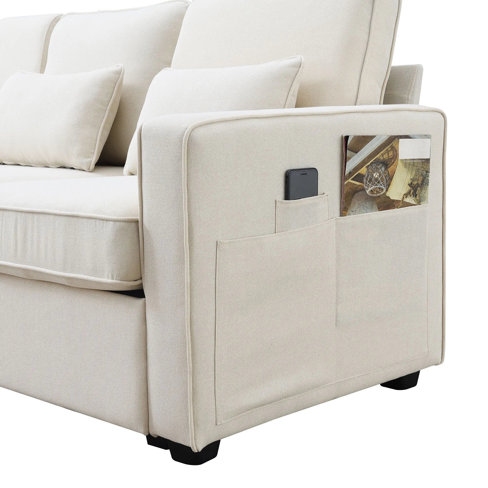 "Beige sofa with a pocket on the armrest containing a phone and a picture frame."