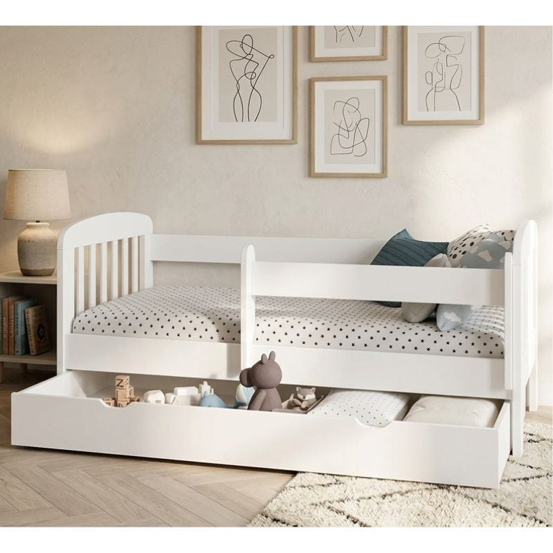 White children's bed with storage drawers in a room with framed art on the wall.