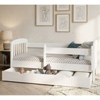 White children's bed with storage drawers in a room with framed art on the wall.