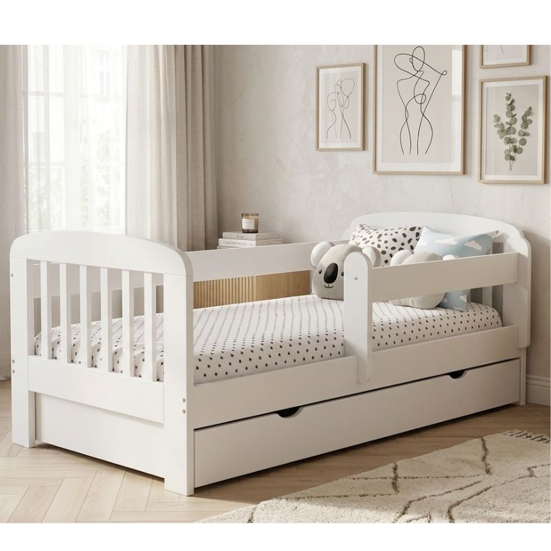 White children's bed with a trundle in a room with framed art on the wall.