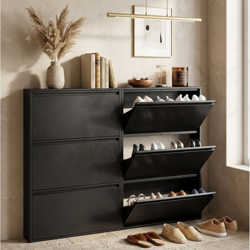 Black shoe cabinet with open drawers displaying shoes, placed against a wall with decor items.