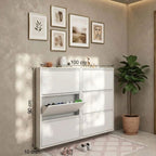 White shoe cabinet with measurements against a beige wall with framed art and a plant.
