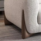 Close-up of a textured sofa with wooden legs on a carpeted floor.