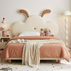 Children's bedroom with a cloud-shaped headboard and pink bedding.