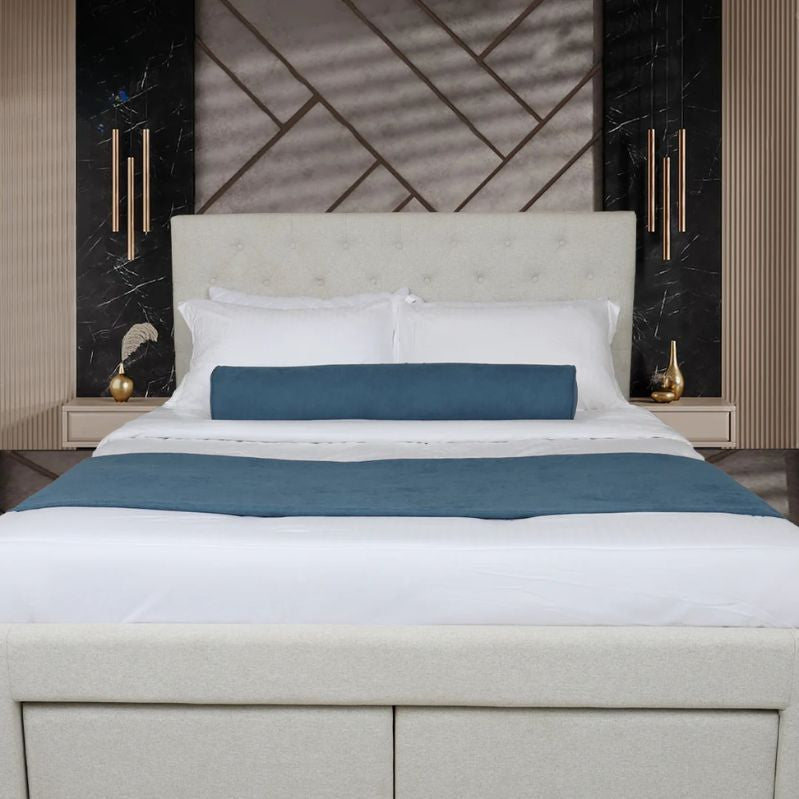 Modern bedroom with a bed featuring white bedding and blue accent pillows, against a decorative wall. 