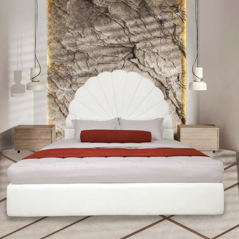 Modern bedroom with a white upholstered bed, red blanket, and stone wall art.