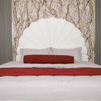 White upholstered headboard with red and gray pillows against a marble wall.