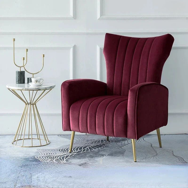 "Maroon armchair in a room with a white wall and small table."