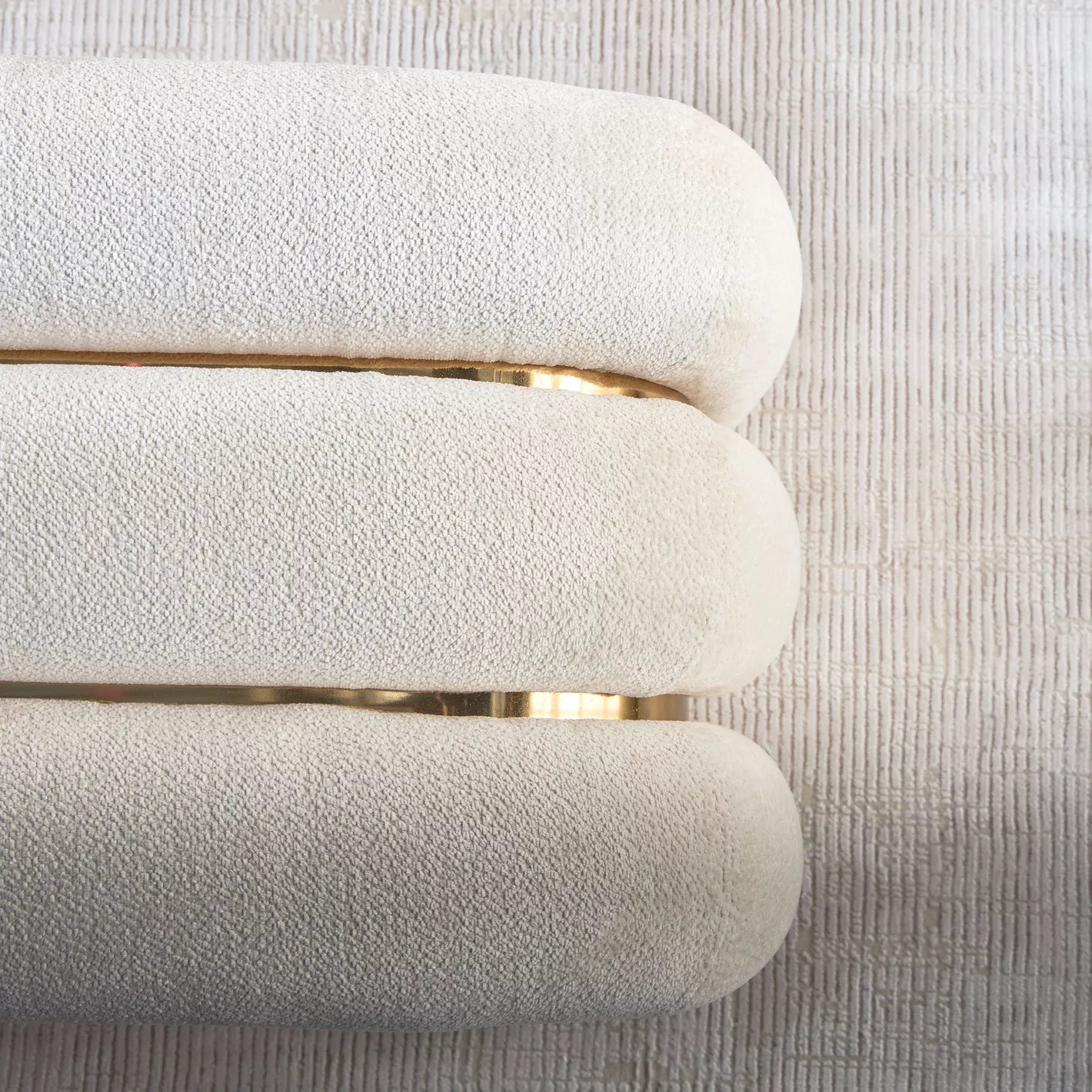 "Close-up of a textured white chair with gold accents on a light gray background"