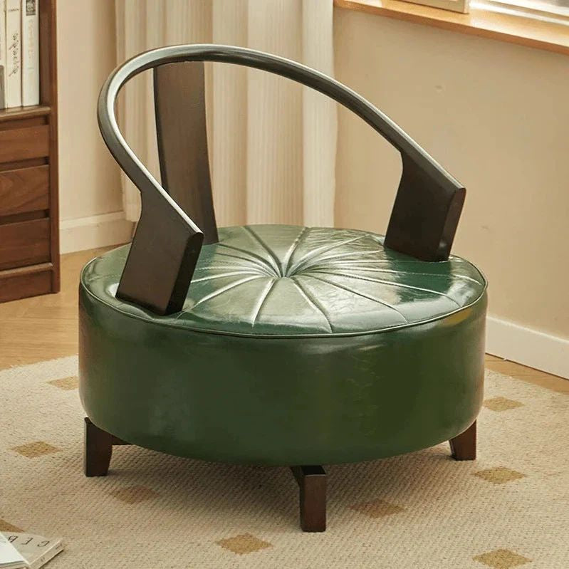 Green leather ottoman with wooden legs in a room setting. Living room furniture, minimalist chair design, circular chair, solid wood chair, aesthetic chair design. 