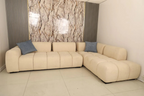 Beige sectional sofa with blue pillows against a patterned wall. Modern sofa design, Sectional sofa, L-shape sofa, Living room sofa. 