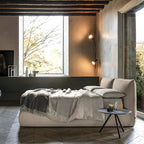 Modern bedroom with a large window, gray sofa, and side table.