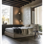 Modern bedroom with a large bed, side table, and large windows.