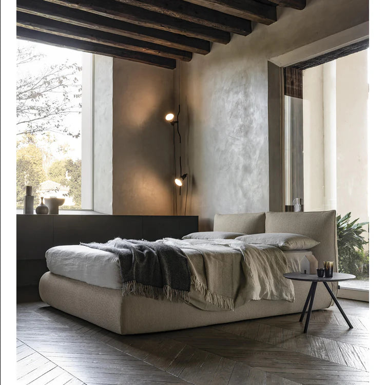 Modern bedroom with a large bed, side table, and large windows.