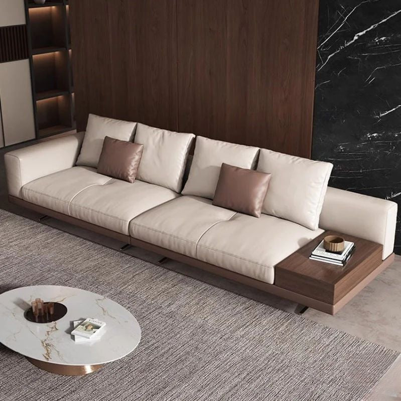 "Philips Modern Modular Puffy Style Sofa With One Sided Wooden Armrest. Modern beige sofa with wooden armrests in a stylish room with marble wall."
