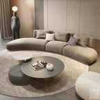 Modern living room with a curved beige sofa, round coffee table, and decorative items.