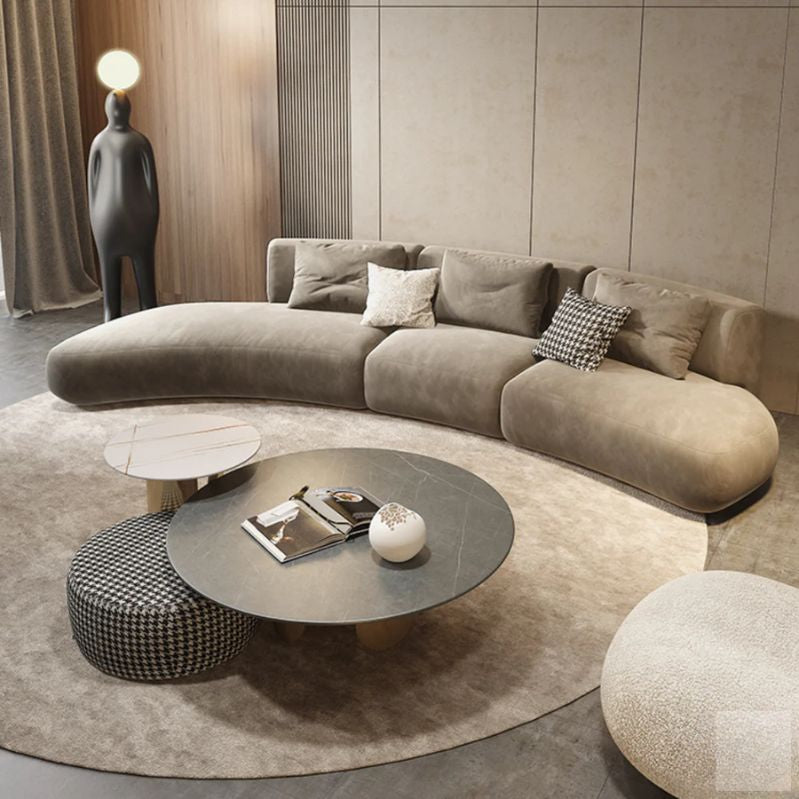 Modern living room with a curved beige sofa, round coffee table, and decorative items.