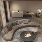 Modern living room with a curved gray sofa, round coffee table, and decorative items.