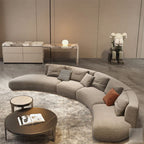 Modern living room with a curved gray sofa, round coffee table, and decorative items.