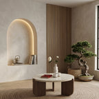 A lifestyle shot of the Terra Marble Coffee Table placed in an aesthetic minimalist interior with a lit architectural wall niche and warm wood paneling